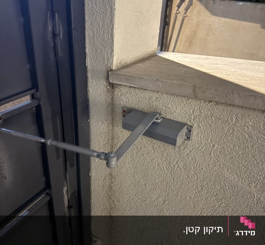 מחזיר דלת הידראולי מותקן על קיר ומחובר לשער מתכת